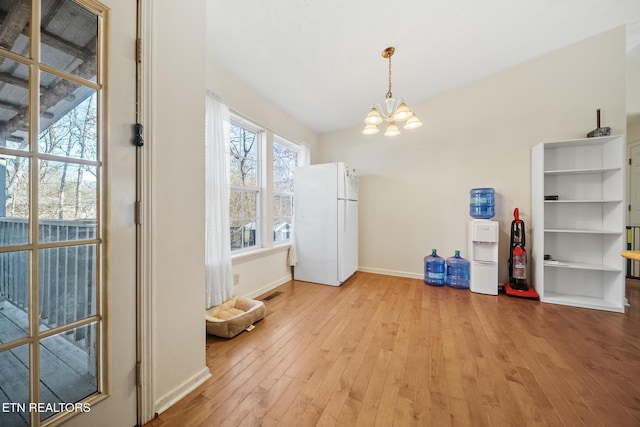 unfurnished dining area featuring visible vents, baseboards, light wood-style flooring, and a notable chandelier