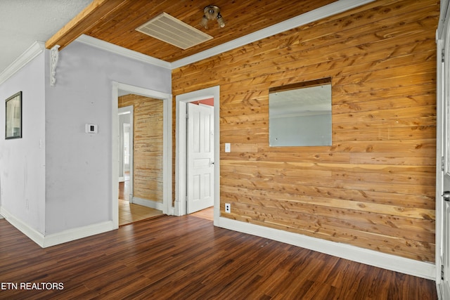 empty room with ornamental molding, wood finished floors, visible vents, and baseboards