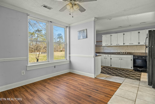 kitchen with black appliances, ornamental molding, visible vents, and white cabinets