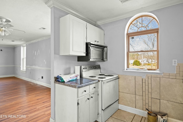 kitchen with dark countertops, white electric range oven, white cabinetry, and ornamental molding