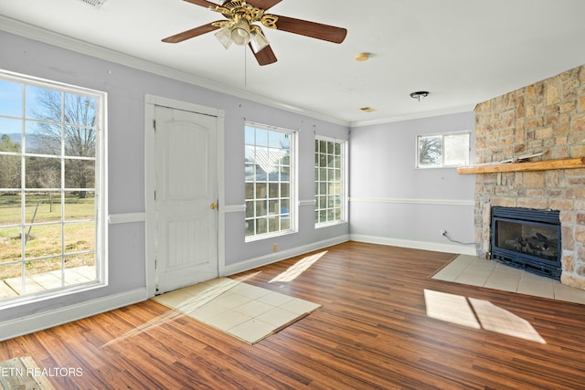 entrance foyer featuring a stone fireplace, ornamental molding, and wood finished floors