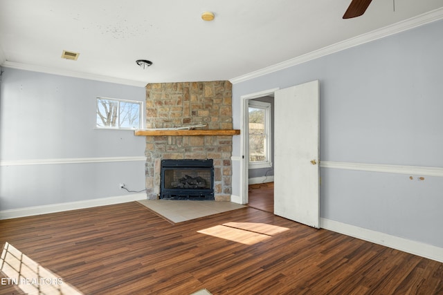 unfurnished living room featuring baseboards, a ceiling fan, wood finished floors, crown molding, and a stone fireplace