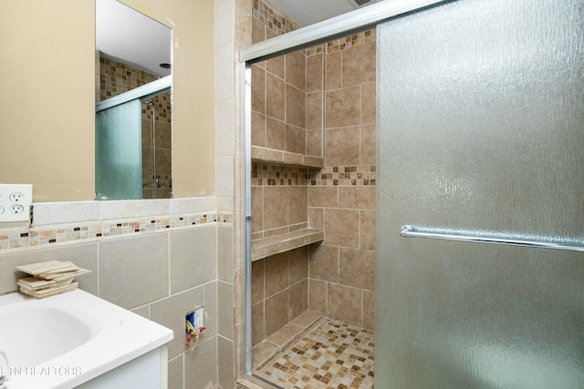 bathroom featuring a stall shower, backsplash, tile walls, and vanity