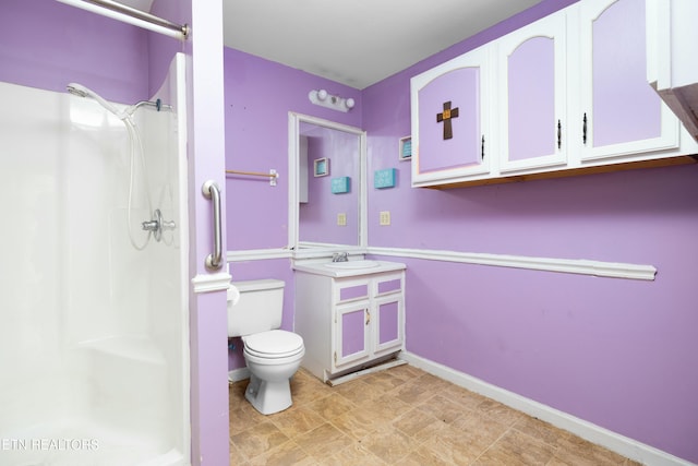 bathroom with baseboards, a shower stall, toilet, and vanity