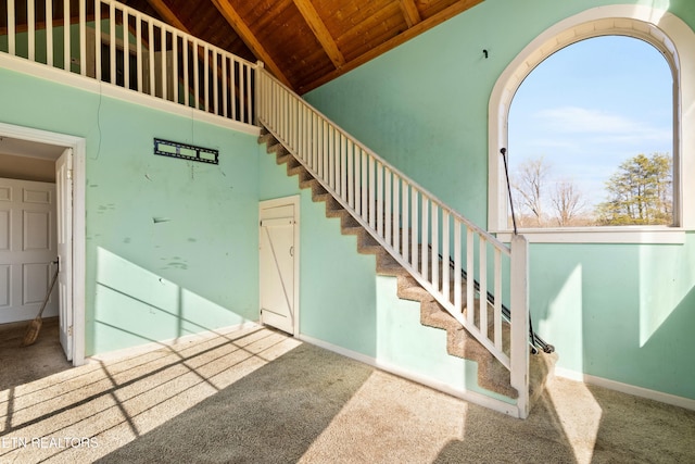 stairway with high vaulted ceiling, carpet, wood ceiling, and baseboards