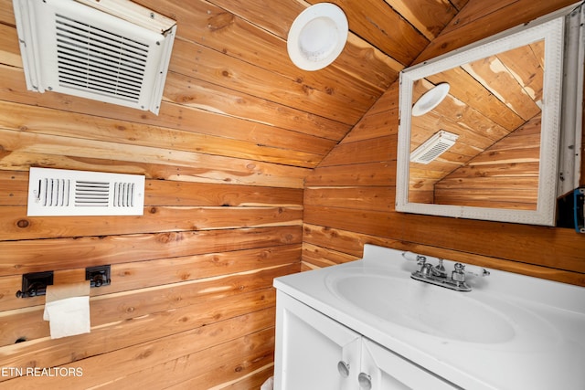 bathroom featuring lofted ceiling, visible vents, wooden walls, and vanity