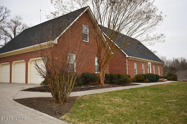 view of home's exterior featuring a garage, brick siding, driveway, and a lawn