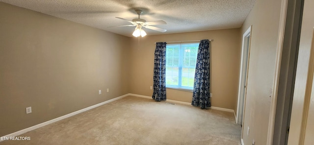 unfurnished room with ceiling fan, a textured ceiling, and light colored carpet