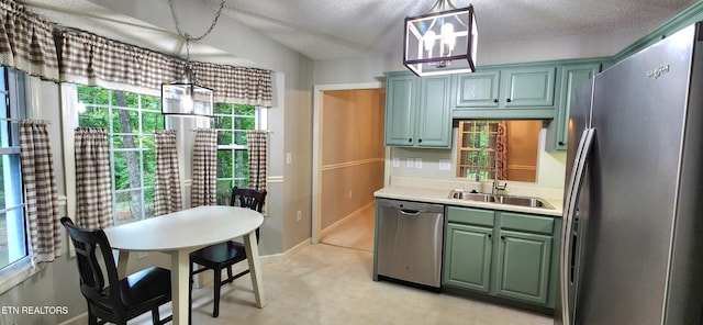 kitchen with appliances with stainless steel finishes, hanging light fixtures, a textured ceiling, green cabinets, and sink