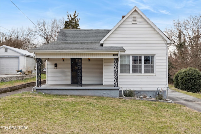 rear view of property with covered porch, a yard, a garage, and an outdoor structure