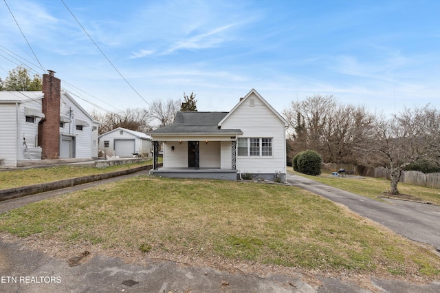 bungalow with a front lawn, a porch, an outdoor structure, and a garage