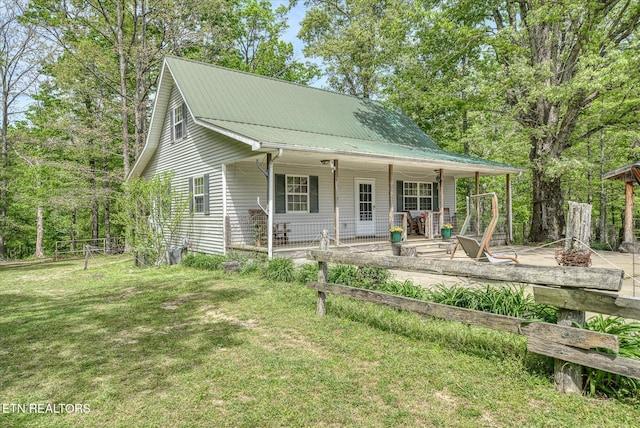 view of front of home with covered porch, metal roof, and a front yard