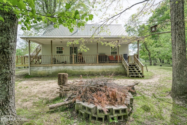 rear view of property with metal roof and stairway