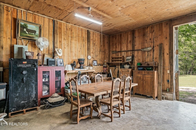 dining area with wooden ceiling, wood walls, and unfinished concrete flooring