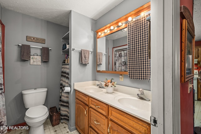 bathroom with toilet, a textured ceiling, double vanity, and a sink