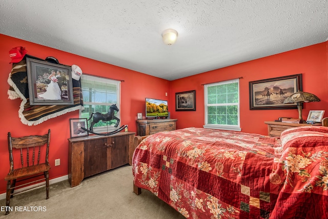 bedroom featuring light carpet, a textured ceiling, and baseboards