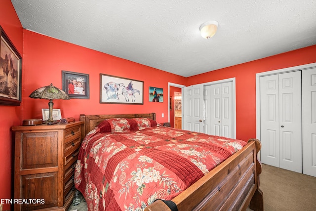 carpeted bedroom featuring a textured ceiling and multiple closets