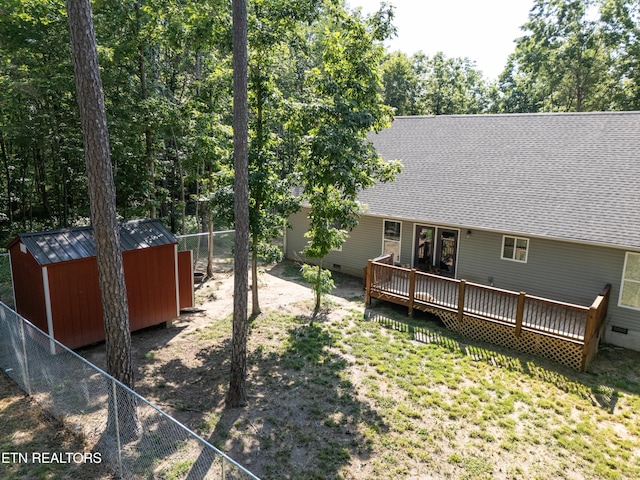 rear view of house with a deck and a storage unit