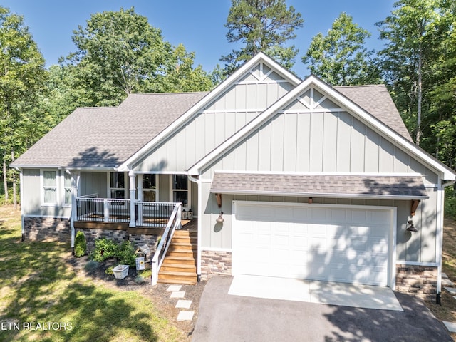 view of front of property featuring covered porch, a front yard, and a garage