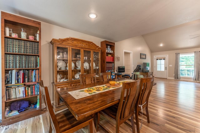 dining space with light wood-type flooring and lofted ceiling