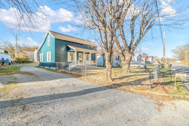 bungalow-style home with driveway, a fenced front yard, and a residential view