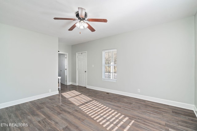 spare room with dark wood-style floors, baseboards, and a ceiling fan