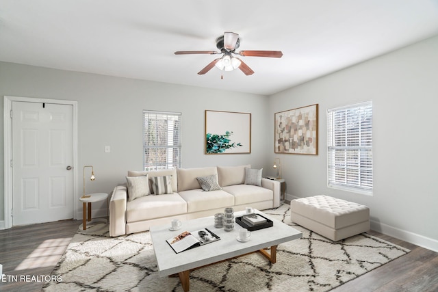 living room featuring a ceiling fan, baseboards, and wood finished floors