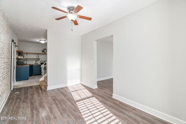 interior space featuring a barn door, baseboards, brick wall, wood finished floors, and stairs