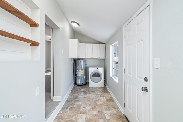 laundry area featuring water heater, cabinet space, stone finish flooring, washer / dryer, and baseboards