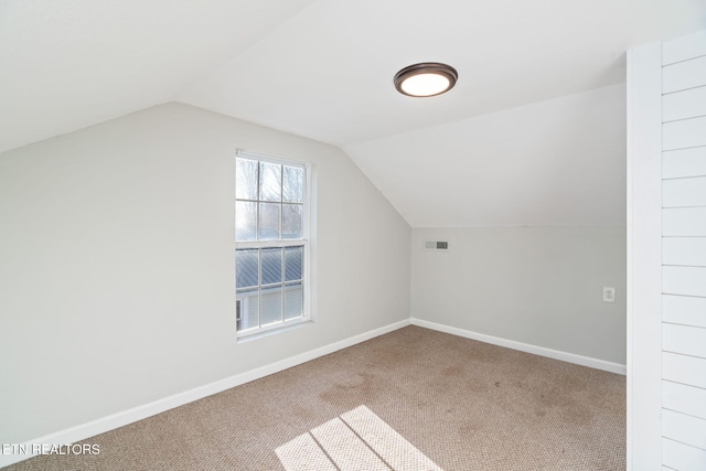 additional living space with lofted ceiling, baseboards, visible vents, and carpet flooring