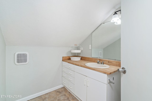 bathroom featuring vaulted ceiling, vanity, and baseboards