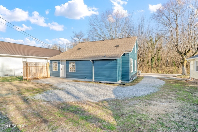 back of property featuring a shingled roof and fence