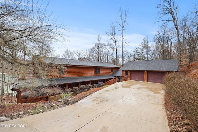 chalet / cabin featuring a garage, a chimney, and an outbuilding