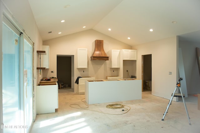 kitchen with white cabinetry, custom exhaust hood, vaulted ceiling, and a center island