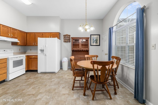 kitchen with white appliances, a chandelier, a healthy amount of sunlight, and decorative light fixtures