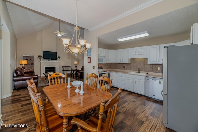 dining area with lofted ceiling, sink, ornamental molding, dark wood-type flooring, and ceiling fan with notable chandelier