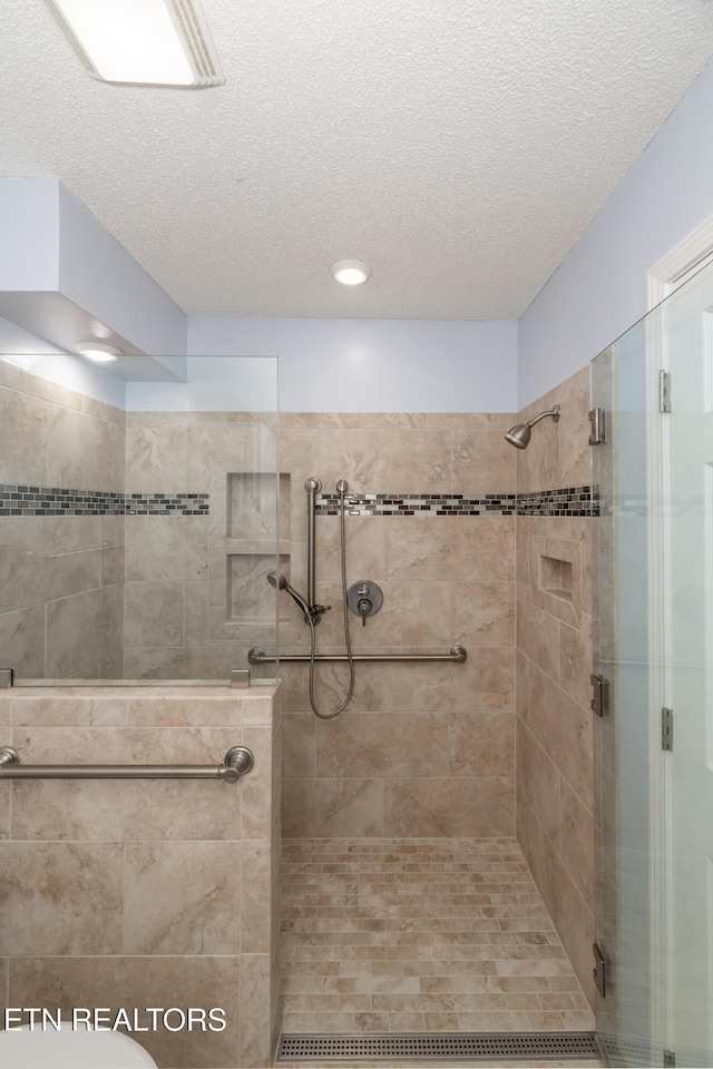 bathroom with a textured ceiling and a shower with shower door