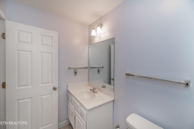 bathroom with toilet, a textured ceiling, and vanity