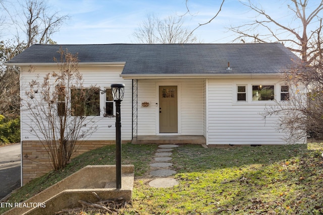 view of front facade featuring roof with shingles, a front lawn, and crawl space