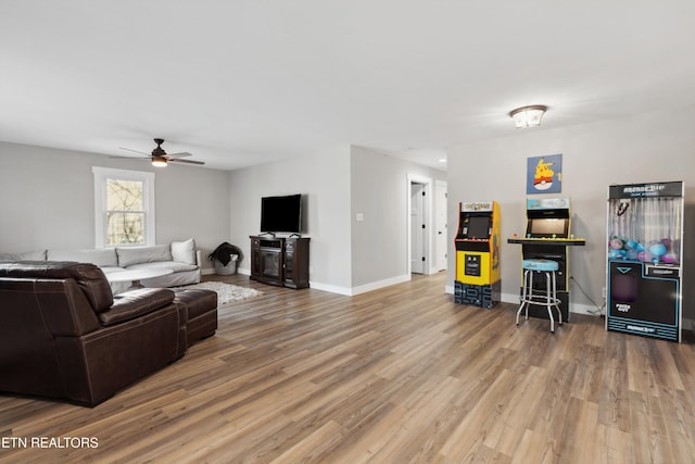 living area with ceiling fan, baseboards, and wood finished floors