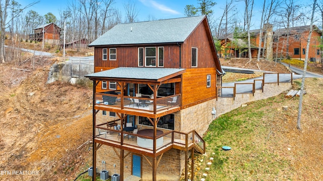 rear view of house with a shingled roof, a balcony, and central air condition unit