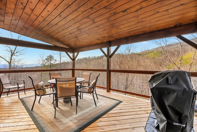 wooden terrace with outdoor dining space and a grill