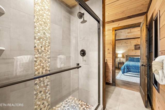 ensuite bathroom with a stall shower, tile patterned flooring, wood walls, and ensuite bathroom