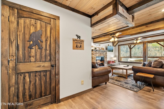 living room featuring wood ceiling, beamed ceiling, a fireplace, and light wood-style flooring