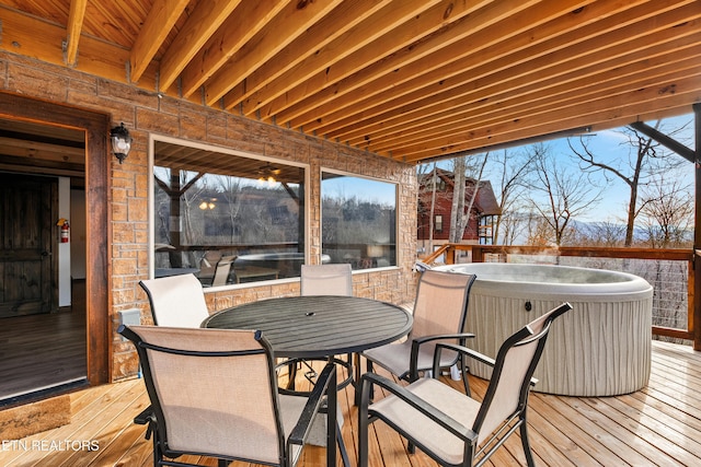 deck with a hot tub and outdoor dining area