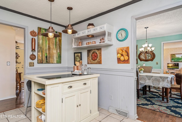 kitchen featuring light hardwood / wood-style flooring, decorative light fixtures, an inviting chandelier, ornamental molding, and a textured ceiling