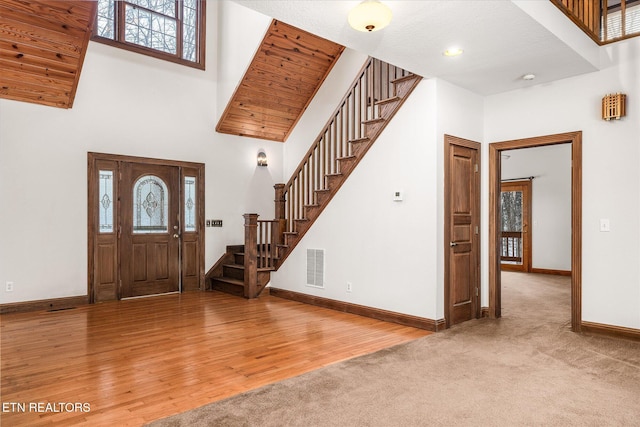 entryway with a high ceiling, wood finished floors, visible vents, baseboards, and stairs