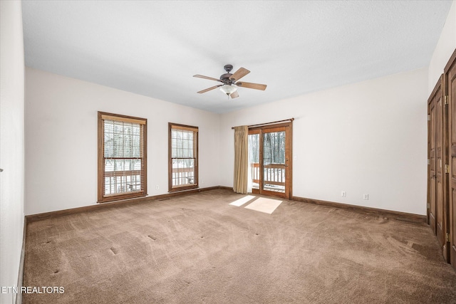 empty room featuring carpet, baseboards, and a ceiling fan