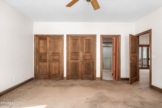 unfurnished bedroom with carpet floors, ceiling fan, baseboards, and two closets