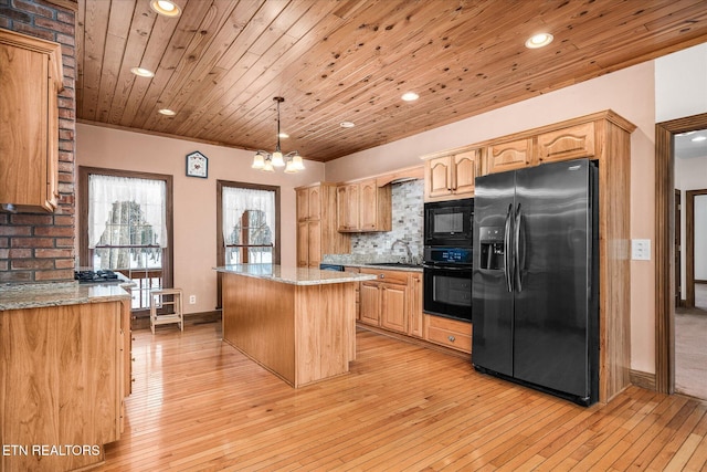 kitchen featuring light stone counters, tasteful backsplash, a sink, a kitchen island, and black appliances